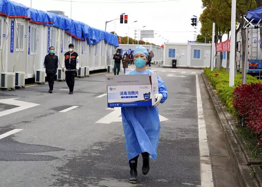 In this photo released by China's Xinhua News Agency, a worker carries a box of supplies at a makeshift hospital in Shanghai, China, Friday, April 15, 2022. Anti-virus controls that have shut down some of China's biggest cities and fueled public irritation are spreading as infections rise, hurting a weak economy and prompting warnings of possible global shockwaves. (Yang Youzong/Xinhua via AP)