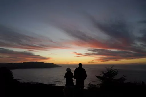 In this Dec. 21, 2020, file photo people watch as the sun sets from the Presidio in San Francisco. The Social Security Administration adjusts its benefits payments each year to reflect changes in the cost of living. The new year will bring a 3.2% increase, much smaller than last year’s 8.7% raise. Even if you’re decades away from retirement, the annual cost of living adjustment can help you predict your potential future payments so you can plan accordingly. (AP Photo/Jeff Chiu, File)