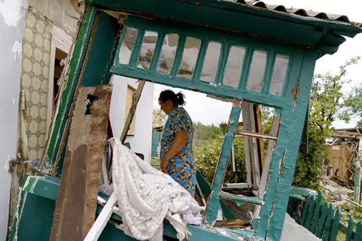 Valentyna Kondratieva, 75, walks into her damaged home Saturday, Aug. 13, 2022, where she sustained injuries in a Russian rocket attack last night in Kramatorsk, Donetsk region, eastern Ukraine. The strike killed three people and wounded 13 others, according to the mayor. The attack came less than a day after 11 other rockets were fired at the city. (AP Photo/David Goldman)