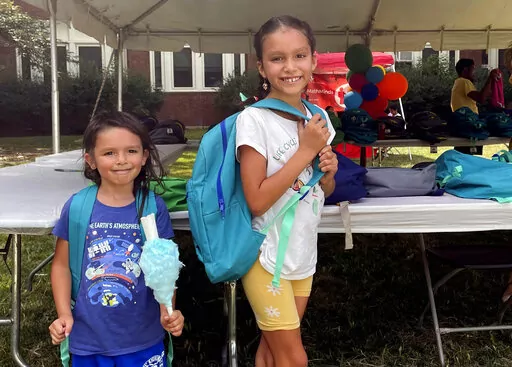 From left, sisters Audrey and Jubilee Colon pick out new backpacks at a Chicago Public Schools back-to-school supply giveaway at Theodore Roosevelt High School in Chicago, on July 22, 2022. This back-to-school shopping season, parents, particularly in the low-to-middle income bracket, are focusing on the basics like no-frills rain boots, while also trading down to cheaper stores, including second-hand clothing, as surging inflation takes a toll on their household budgets. (AP Photo/Claire Savage