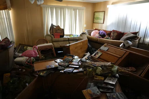 Furniture and personal items lie jumbled in the living room of Nita Ross, 79, as she returns to her mobile home for the first time since the passage of Hurricane Ian, at the Sunshine Mobile Home Park in Fort Myers, Fla., Saturday, Oct. 1, 2022. Ross' home stayed on its foundations, unlike those of some of her neighbors, but storm flooding almost to the height of the ceiling destroyed most of her possessions and household items. (AP Photo/Rebecca Blackwell)