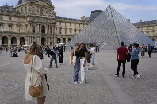 Tourists take pictures in front of the Pyramid in the Louvre Museum courtyard in Paris, France, on June 20, 2022.  Travel to Europe might be an attractive option to travelers looking for a budget vacation in 2022. The dollar is strong this year, meaning your cash can go further on the continent. (AP Photo/Francois Mori)