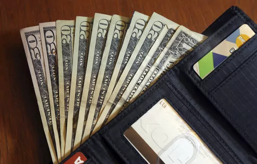 In this June 15, 2018, file photo, cash is fanned out from a wallet in North Andover, Mass. As you plan your holiday giving, you may be thinking about adding service workers to your list of recipients. (AP Photo/Elise Amendola, File)
