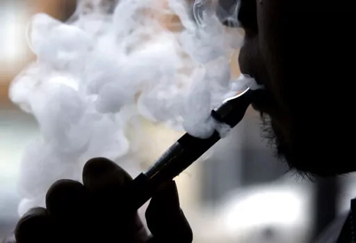 In this April 23, 2014 file photo, a man smokes an electronic cigarette in Chicago. Food and Drug Administration officials on Friday, Feb. 24, 2023 pledged a reset in the agency’s tobacco program, responding to criticisms that a lack of direction has hampered federal efforts to regulate cigarettes, vaping devices and other industry products.(AP Photo/Nam Y. Huh, File)