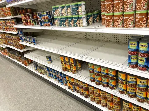Racks sit devoid of product in a Target store Tuesday, March 15, 2022, in Sheridan, Colo. The U.S. economy ended 2021 by expanding at a healthy 6.9% annual pace from October through December, the government reported Wednesday, March 30, a slight downgrade from its previous estimates. For the January-March quarter of this year, the biggest drag will be a sharp reduction in the amount of goods businesses restock on their shelves and warehouses.   (AP Photo/David Zalubowski)